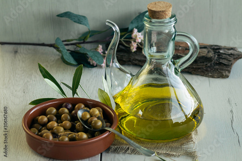  Olive oil and Arbequina olives on birch wood  glass bowl to pour olive oil. Also olive tree leaves photo