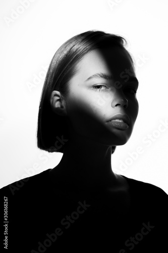 Fashionable beauty portrait. Black silhouette on white background. Girl with a spot of light on her face. 