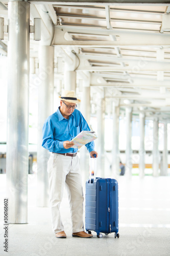 Senior man traveling with luggage checking city map and sightseeing. Senior man Travel and tourism concept.