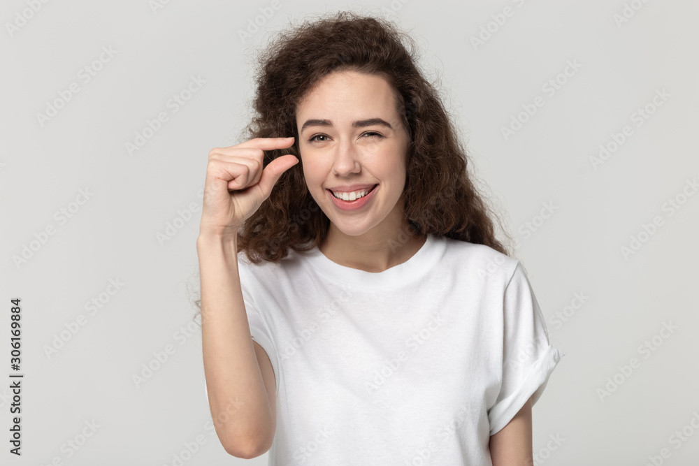 Smiling millennial girl show small measurement with hands Smiling millennial girl show small measurement with hands