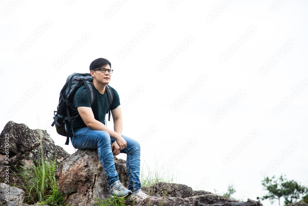 Fototapeta premium Traveler Man relaxing sitting on top of cliff in summer rockmountains on white background. Travel Lifestyle hiking concept summer vacations outdoor
