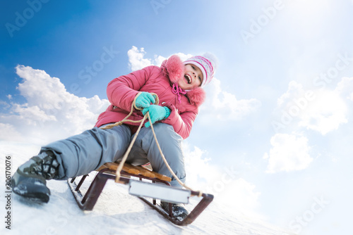 Happy girl sledding outdoors on clear winter day