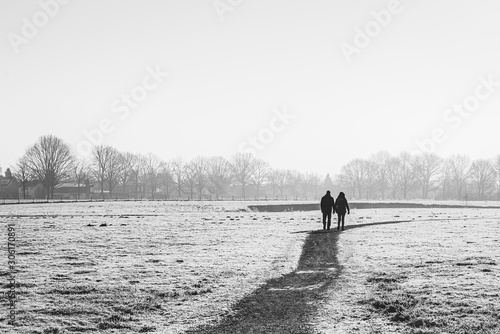 Obraz na płótnie Man and woman walk together on a meandering path in winter time w salonie