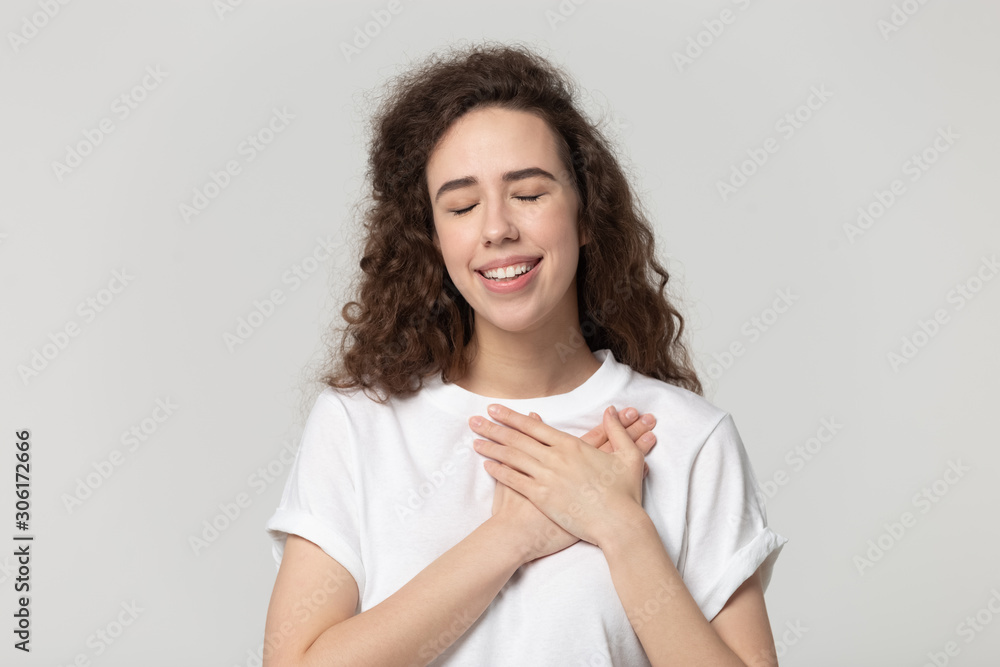 Thankful millennial girl with hands at chest feel gratitude Thankful millennial girl with hands at chest feel gratitude