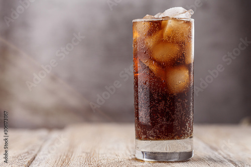 Cola with Ice Cubes. Glass of cola with ice cubes on wood table, soft drink. Copy Space. photo