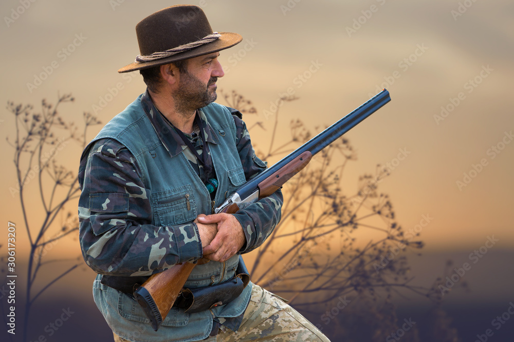Hunting period, autumn season open. A hunter with a gun in his hands in hunting clothes in the autumn forest in search of a trophy. A man stands with weapons and hunting dogs tracking down the game... Hunting period, autumn season open. A hunter with a gun in his hands in hunting clothes in the autumn forest in search of a trophy. A man stands with weapons and hunting dogs tracking down the game...