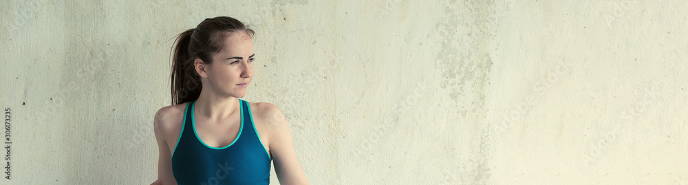 Athletic girl looks into the distance. Toned panoramic image on a background of a brick wall with concrete. Athletic girl looks into the distance. Toned panoramic image on a background of a brick wall with concrete.