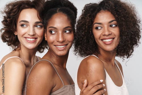 Portrait of three charming multiethnic women smiling and looking aside