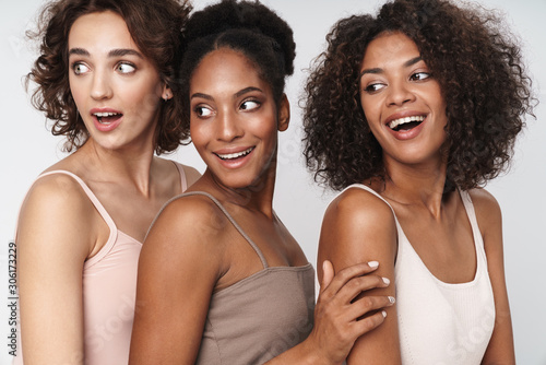 Portrait of three delighted multiethnic women smiling and looking aside