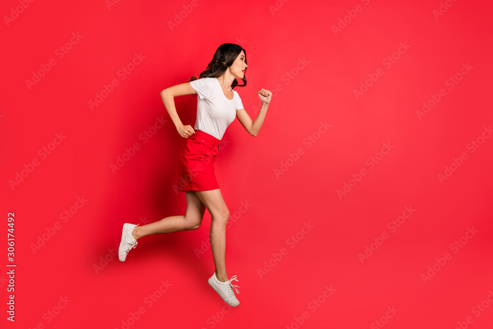 Full length body size profile side view of her she nice attractive lovely pretty serious slim fit wavy-haired girl jumping running fast isolated over bright vivid shine vibrant red color background Full length body size profile side view of her she nice attractive lovely pretty serious slim fit wavy-haired girl jumping running fast isolated over bright vivid shine vibrant red color background