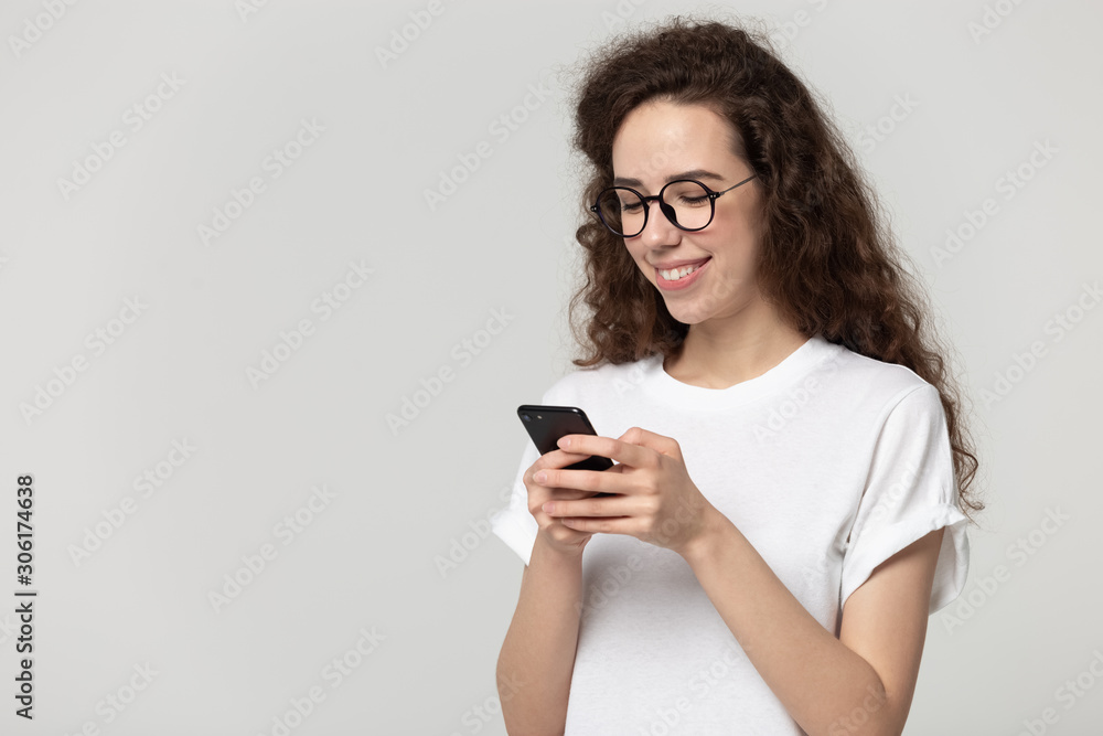 Smiling millennial girl texting using modern cellphone Smiling millennial girl texting using modern cellphone