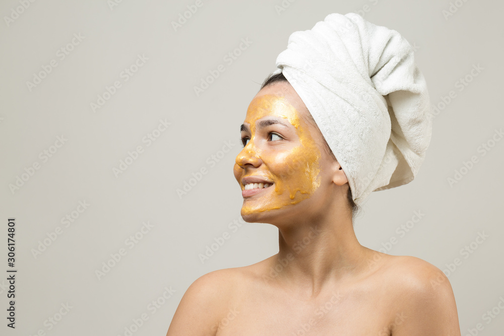 Beauty portrait of woman in white towel on head with gold nourishing mask on face. Skincare cleansing eco organic cosmetic spa relax concept. Beauty portrait of woman in white towel on head with gold nourishing mask on face. Skincare cleansing eco organic cosmetic spa relax concept.