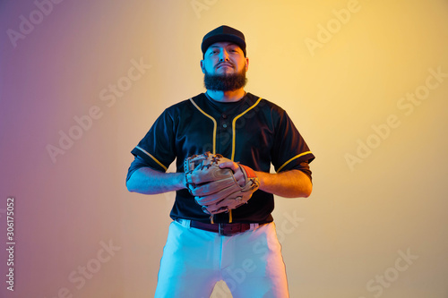 Photography Baseball player, pitcher in a black uniform practicing and training on gradient background in neon light