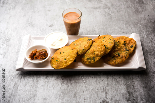 Methi Poori or Puri made using Fresh fenugreek leaves missed with wheat flour, by making small pancake size shapes deep fried in oil, served with tea photo