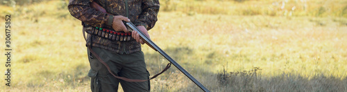 Hunter with a hat and a gun in search of prey in the steppe, Aims for prey. Panoramic image for your text, toned.