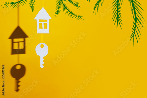small house and key made of cardboard casts a shadow on a bright colored background