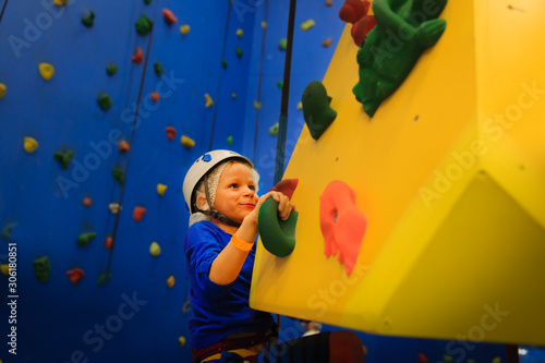 little boy climbing wall in sport center
