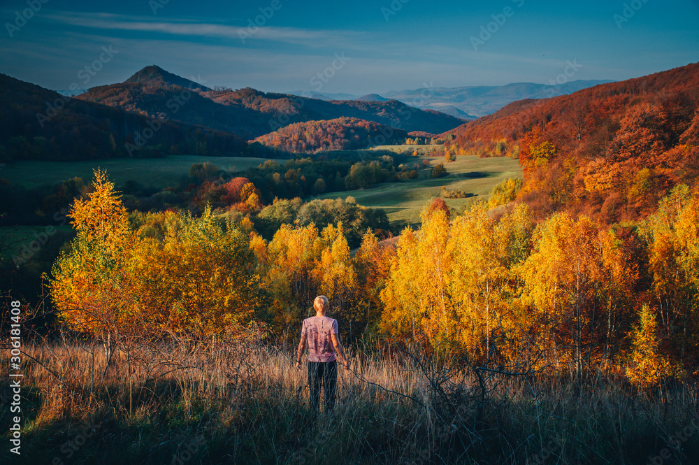 Man looking at beautiful autumn landscape in warm evening light