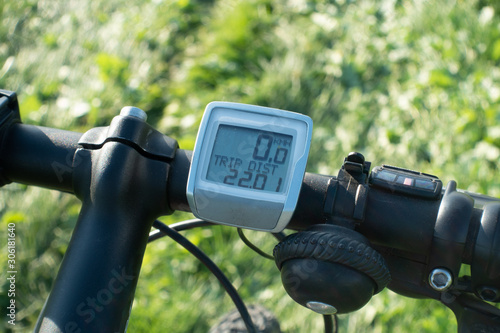 Bicycle handlebar with bike computer and bell. Blurred background of green grass.