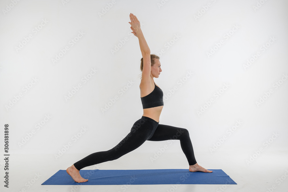 Sporty attractive young woman doing yoga practice on white background. Warrior, Virabhadrasana.