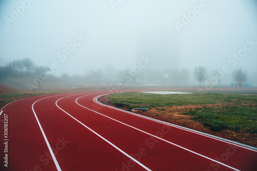 Truck and Field concept photo. Red athletics track in morning mist. Running photo, white edit space