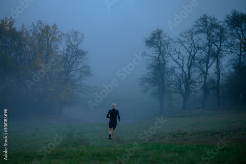 Runner in grey autumn misty morning, active life even in bad weather