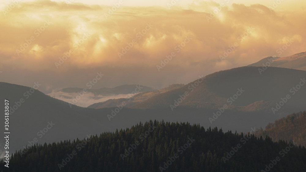 Mountain range with visible silhouettes through the morning colorful fog.Tarcu Mountains in Romania.
