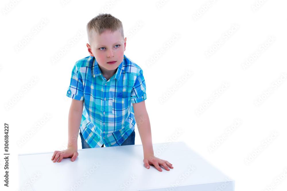 A beautiful little boy is photographed near a white cube. The co A beautiful little boy is photographed near a white cube. The co