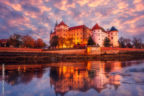 Wonderful sunrise view of Schloss Hartenfels, with colorful sky reflected in Elbe river . Picturesque morning view of castle on banks of the Elbe. Torgau. Saxony, Germany. creative Scenic image