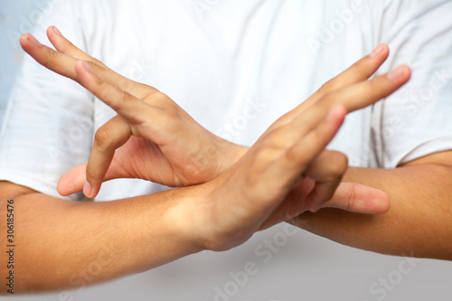 Isolated hands of male teenager doing Bhutadamar Yoga Mudra/ Shuni Yoga mudra wearing a white t-shirt.Horizontal shot. photo