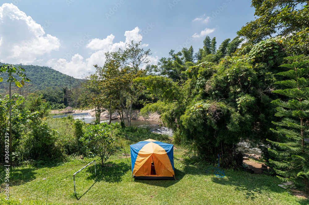 Tent camping on lawn with blue sky in tropical rainforest at countryside