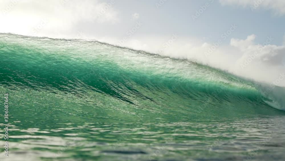 SLOW MOTION, beautiful backlit blue barrel wave crashing over in water housing. Amazing shot of large tube wave with mountains in background