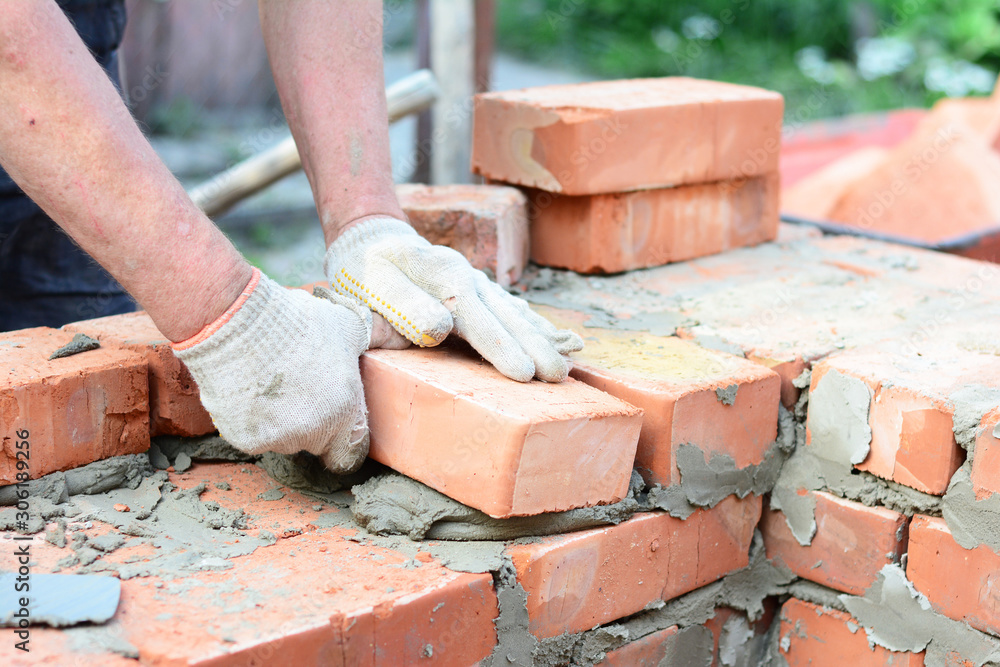 Bricklaying house wall, masonry. Bricklayer hands in masonry gloves