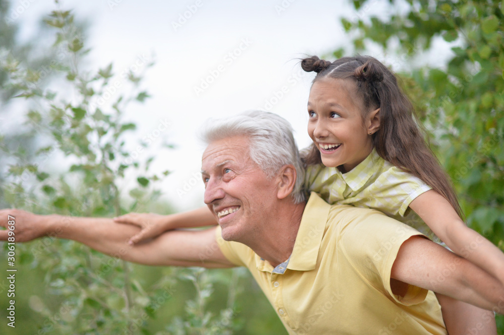 Portrait of happy grandfather and granddaughter having fun in park