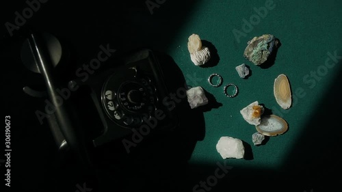 On the billiard table is an old telephone with a round dial, stones and jewelry lie nearby. photo