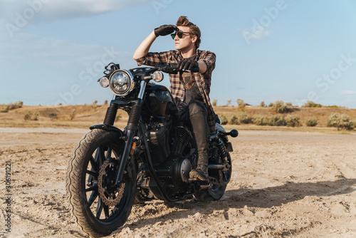 Fototapeta Naklejka Na Ścianę i Meble -  Concentrated serious young man biker outdoors