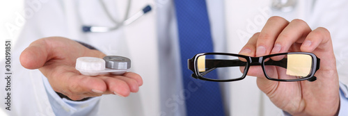 Male doctor hands giving pair of black glasses and contact lens