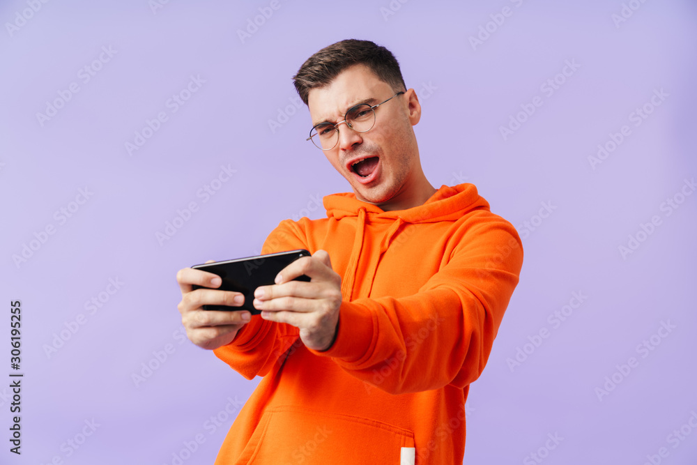 Emotional concentrated young man play games by mobile phone. Emotional concentrated young man play games by mobile phone.