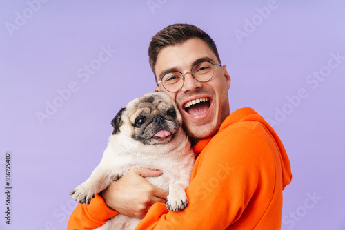 Cheery optimistic man holding hugging dog pug. photo