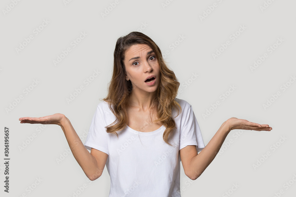 Confused attractive young woman shrugging shoulders, looking at camera Confused attractive young woman shrugging shoulders, looking at camera