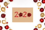 2020 made of red sparkles and decorative christmas toys on craft sheet of paper.