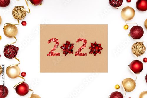 2020 made of red sparkles and decorative christmas toys on craft sheet of paper.