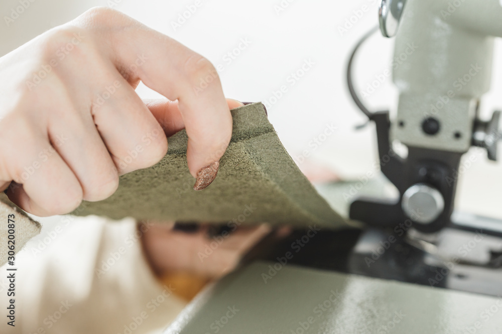 Woman stitching leather using a sewing machine Woman stitching leather using a sewing machine