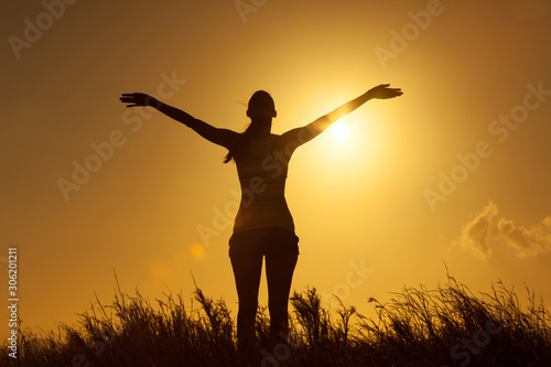 Feeling good, and full on happiness. Happy woman with arms up to the sunset. 