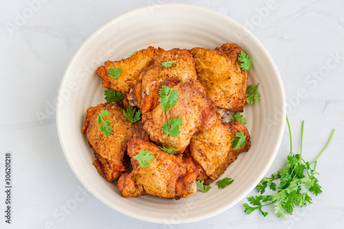 Crispy Oven Fried Chicken Thighs in a Bowl on White Background, Top View Food Photography.