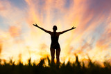 Woman with arms up tot he sunset. Happiness and feeling at peace in nature. 