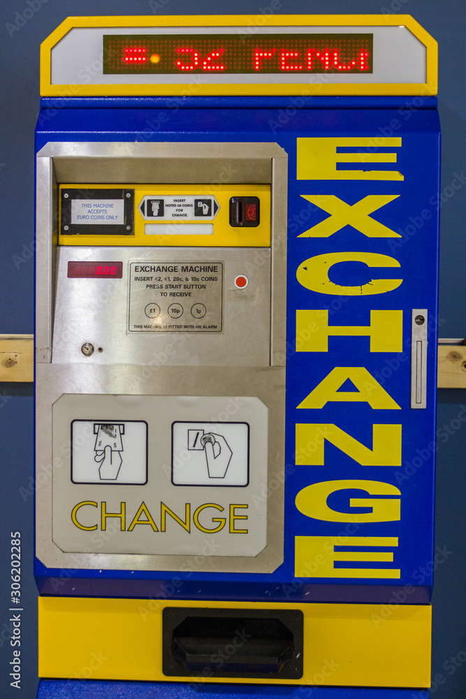 England 15/05/2019 Old vintage retro money cash exchange machine in arcade play area customers gain very old antique still running working bright yellow blue coloured metal dirty change notes coins