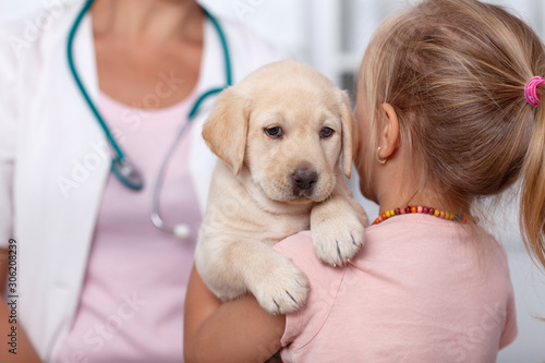 Little girl holding her puppy at the veterinary healthcare clinic