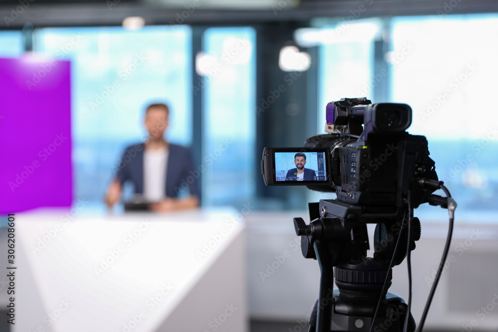 Presenter working in studio, focus on video camera Presenter working in studio, focus on video camera