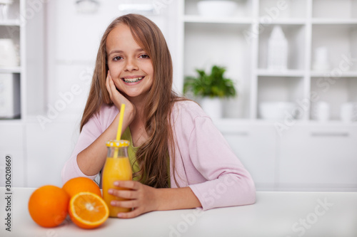 Young teenager girl with broad smile and freshly squeezed orange juice in the kitchen © Ilike